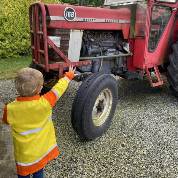 a young firefighter in his uniform looking at a red fire engine.