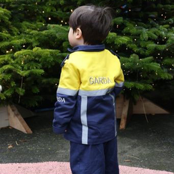 a young firefighter in his uniform looking at a red fire engine.