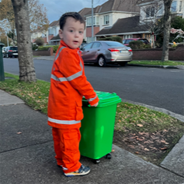 a young firefighter in his uniform looking at a red fire engine.